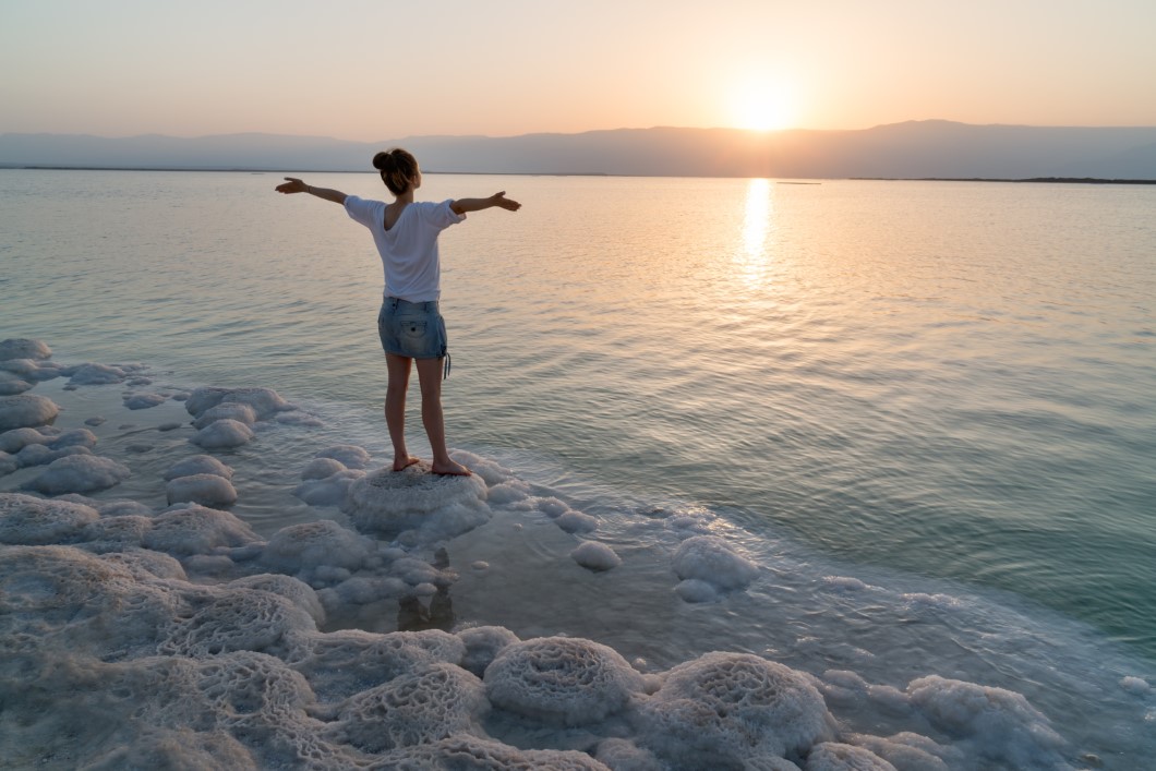 Girl meets sunrise on the shore the Dead Sea