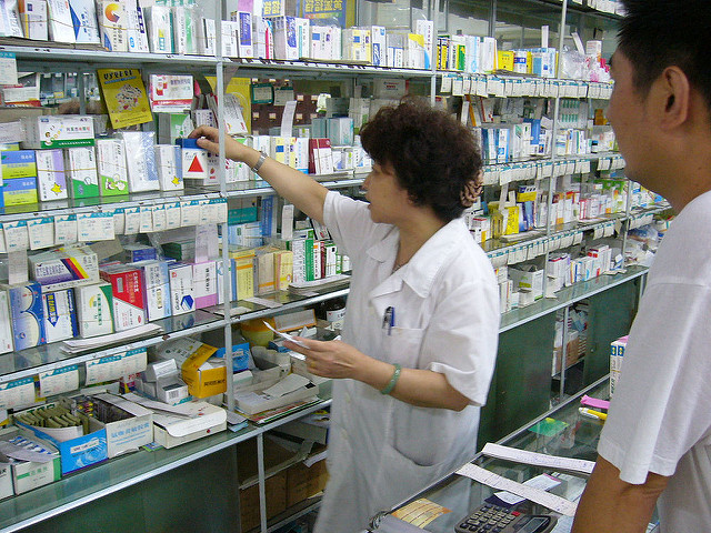 Chinese pharmacy technician grabbing medicine for customer