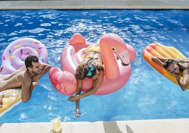 Spain, Andalusia, cadiz, El Puerto de Santa Maria, Friends in pool mounted on ice cream and flamingo floats.