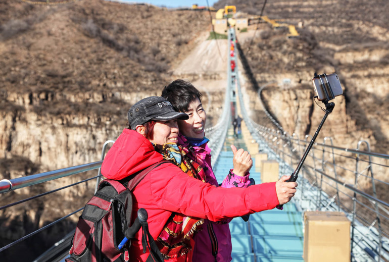(171224) -- SHIJIAZHUANG, Dec. 24, 2017 (Xinhua) --  Tourists pose for photos on the glass suspension bridge at Hongyagu scenic spot in Pingshan County, north China's Hebei Province, Dec. 24, 2017. The 488-meter-long glass suspension bridge was formally open to the public Sunday. (Xinhua/Liu Peiran) (yxb) (Photo by Xinhua/Sipa USA)